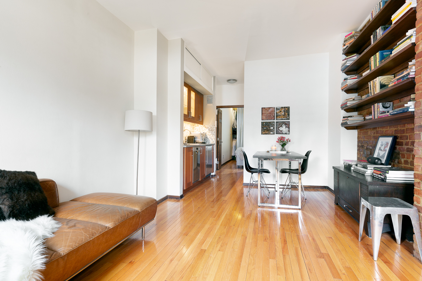 438 49TH ST W 5B Manhattan, New York Move in ready, contemporary top floor apartment with peaceful inner courtyard and city views. Pin drop quiet and yet in the heart of all that Hell's Kitchen has to offer is this stylish renovated true one-bedroom/one-bathroom co-op apartment.
Whether you are looking for full-time residency or a pied-a-terre, this building, on a quiet tree lined block, is very flexible; allowing parent purchasing for children, co-purchase, gifting and unlimited leasing after four years of owner occupancy. Apartment 5B has wonderful high ceilings, an exposed brick wall lined with gorgeous oak shelves, new hardwood floors and an abundance of natural light from the South facing living room windows, looking out over Midtown and the courtyard. The kitchen has been completely renovated with new custom cabinetry, open shelves, counter top and backsplash, new stainless steel appliances including a Bosch super silent dishwasher, Summit professional grade refrigerator, Delonghi smart oven and Summit cooktop. The windowed bathroom is tiled throughout, with a new floor and a large walk-in shower. The Queen size bedroom at the end of the apartment faces East onto the side of the building and has a walk-in, custom designed, floor to ceiling adjustable closet. This well maintained building features a central laundry, individual storage crate and bike storage for rent, all conveniently located in the basement. As an extra bonus, this apartment is being sold with the stylish new furnishings and window treatments included in the price. Pets allowed (dogs under 25lb).